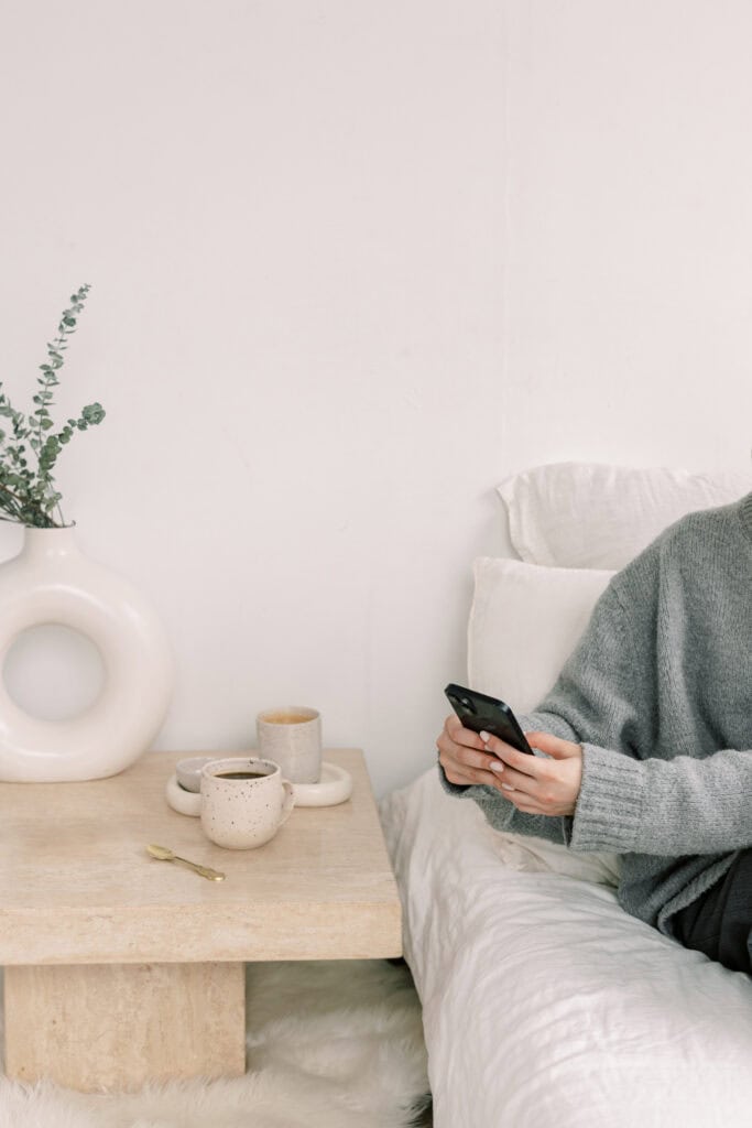 Woman sitting in bed messaging on her phone