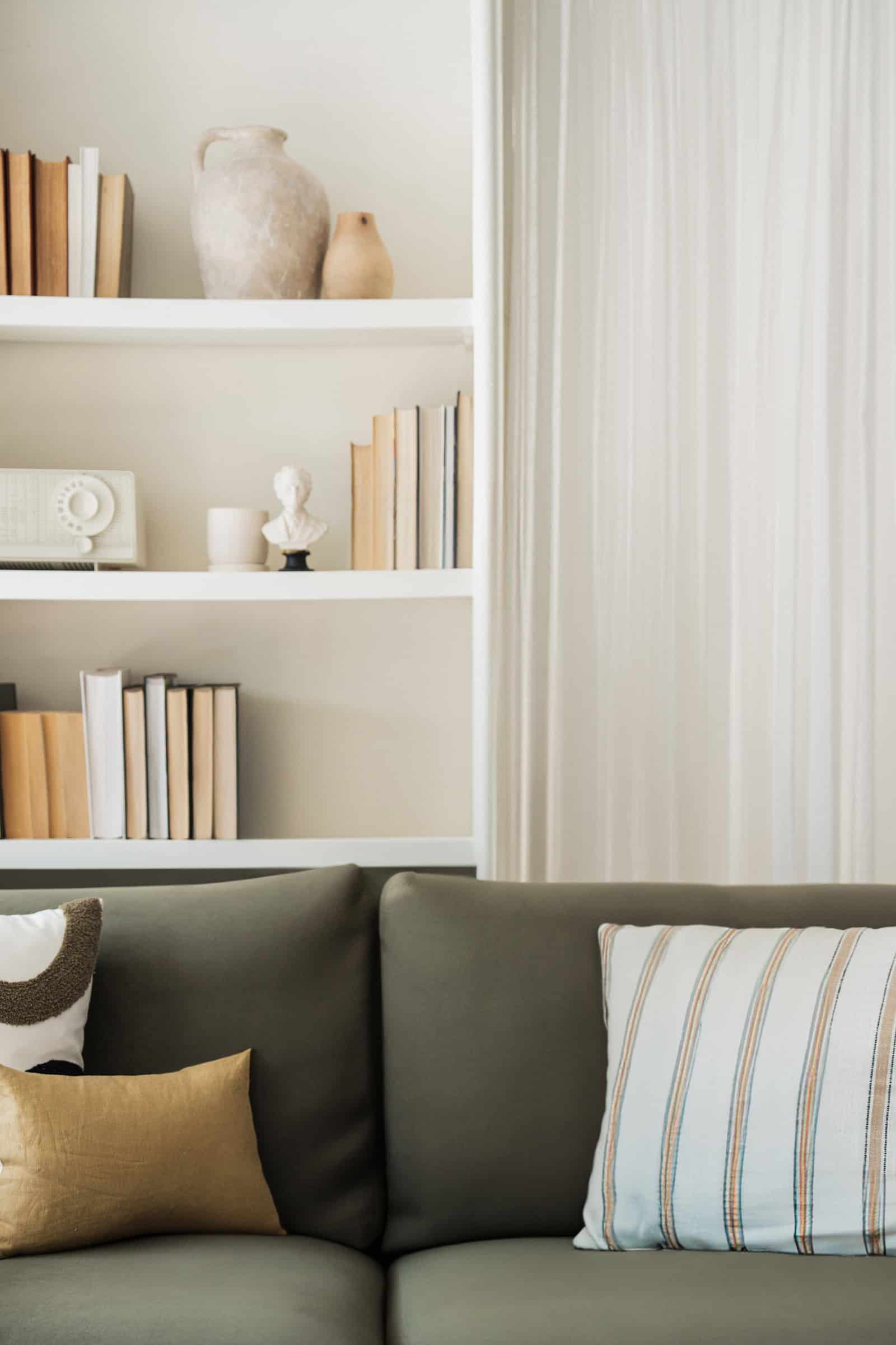 Green couch in front of white bookshelf